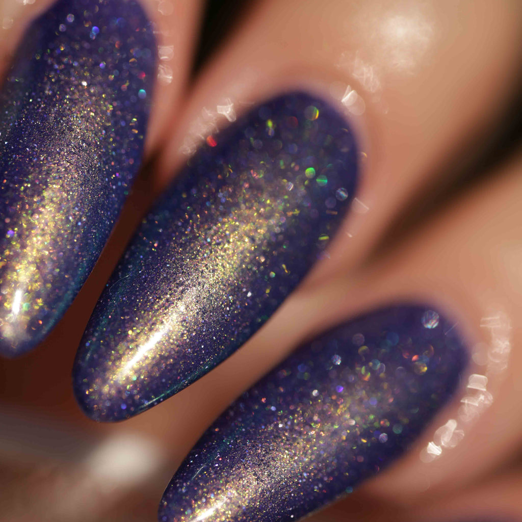 Close-up of a hand with long almond-shaped nails painted in a deep purple nail polish with dense gold and iridescent holographic glitter.